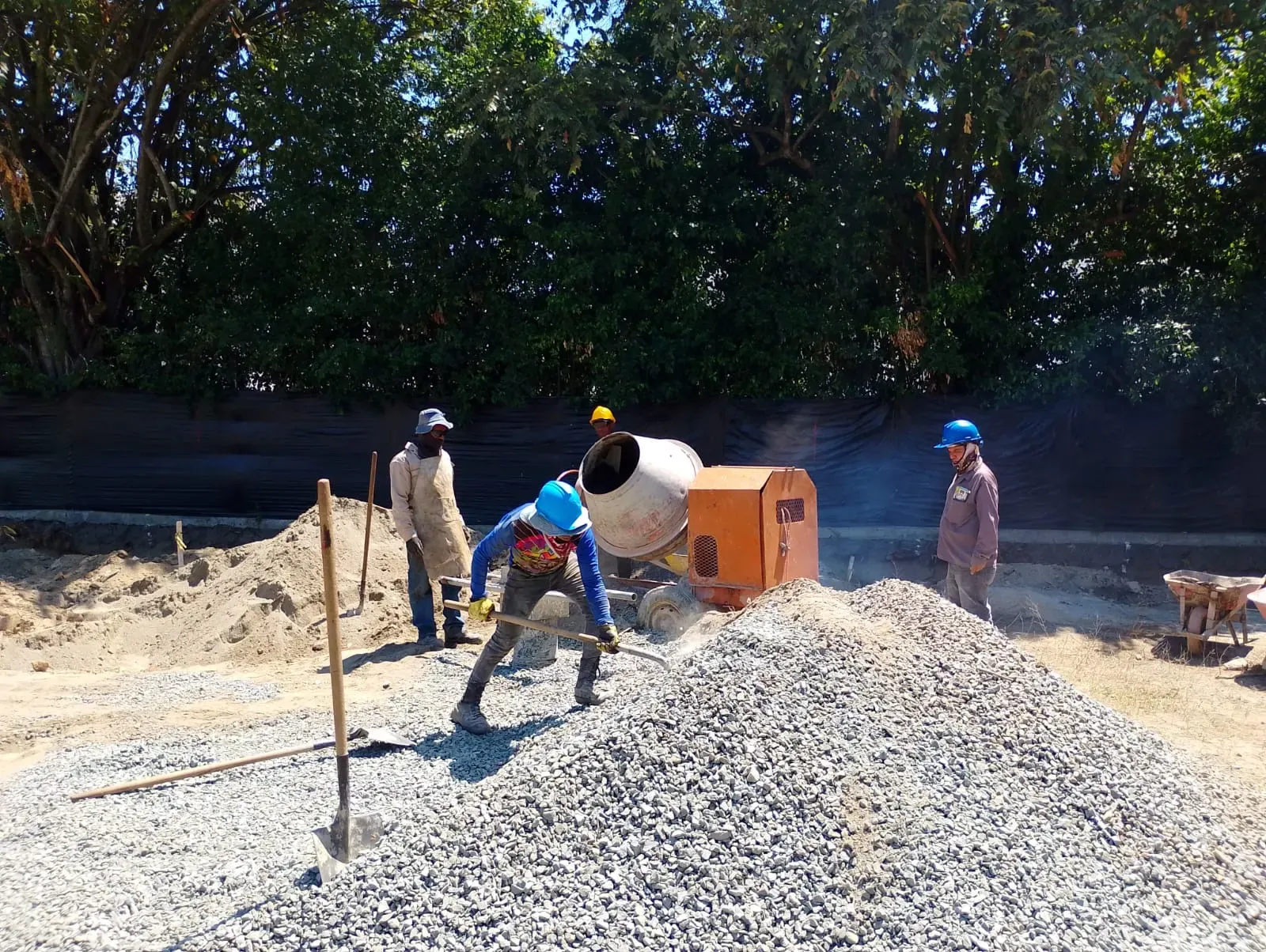 Cuadrilla preparando mezcla de concreto junto a la mezcladora en obra.