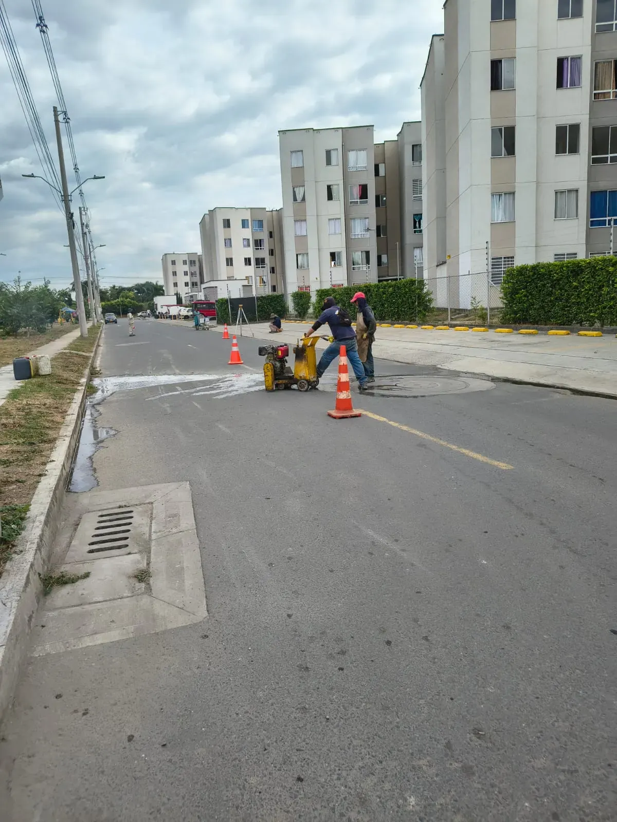 Corte de pavimento señalizado con conos sobre una vía urbana en servicio.