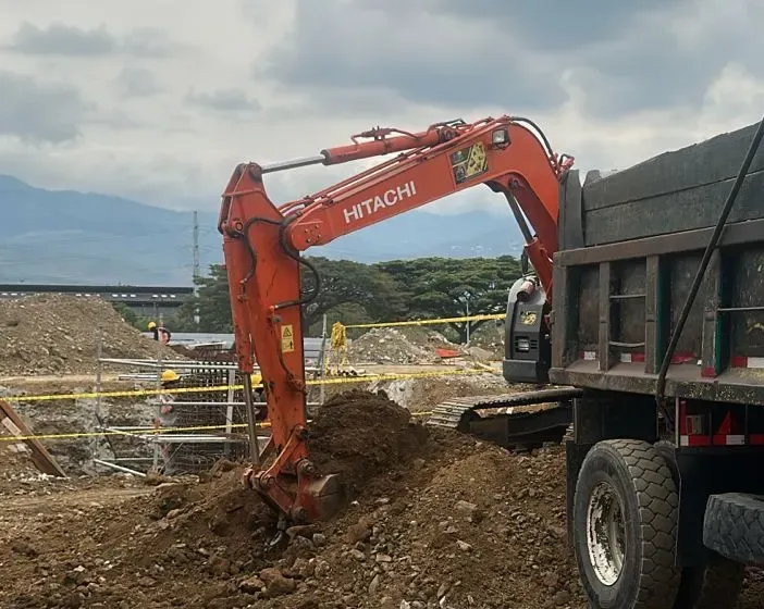 Excavadora Hitachi cargando material sobre una volqueta en un frente de obra.