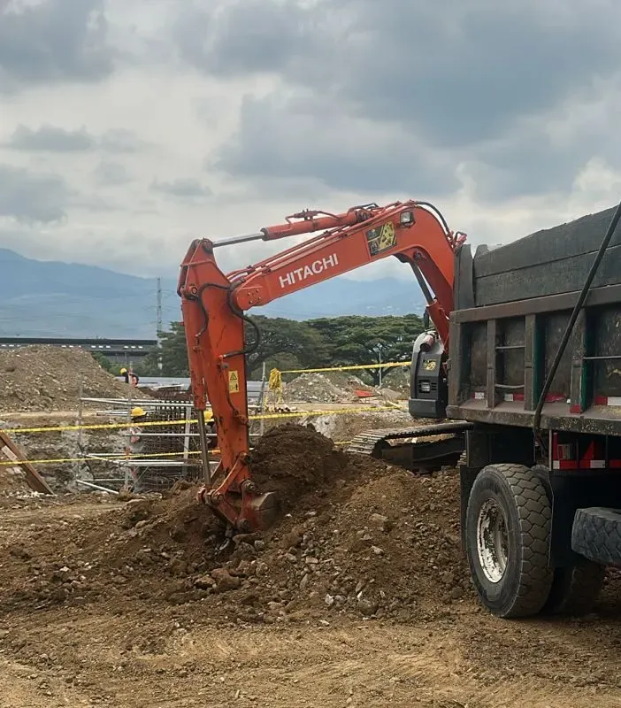 Excavadora Hitachi cargando material sobre una volqueta en un frente de obra.