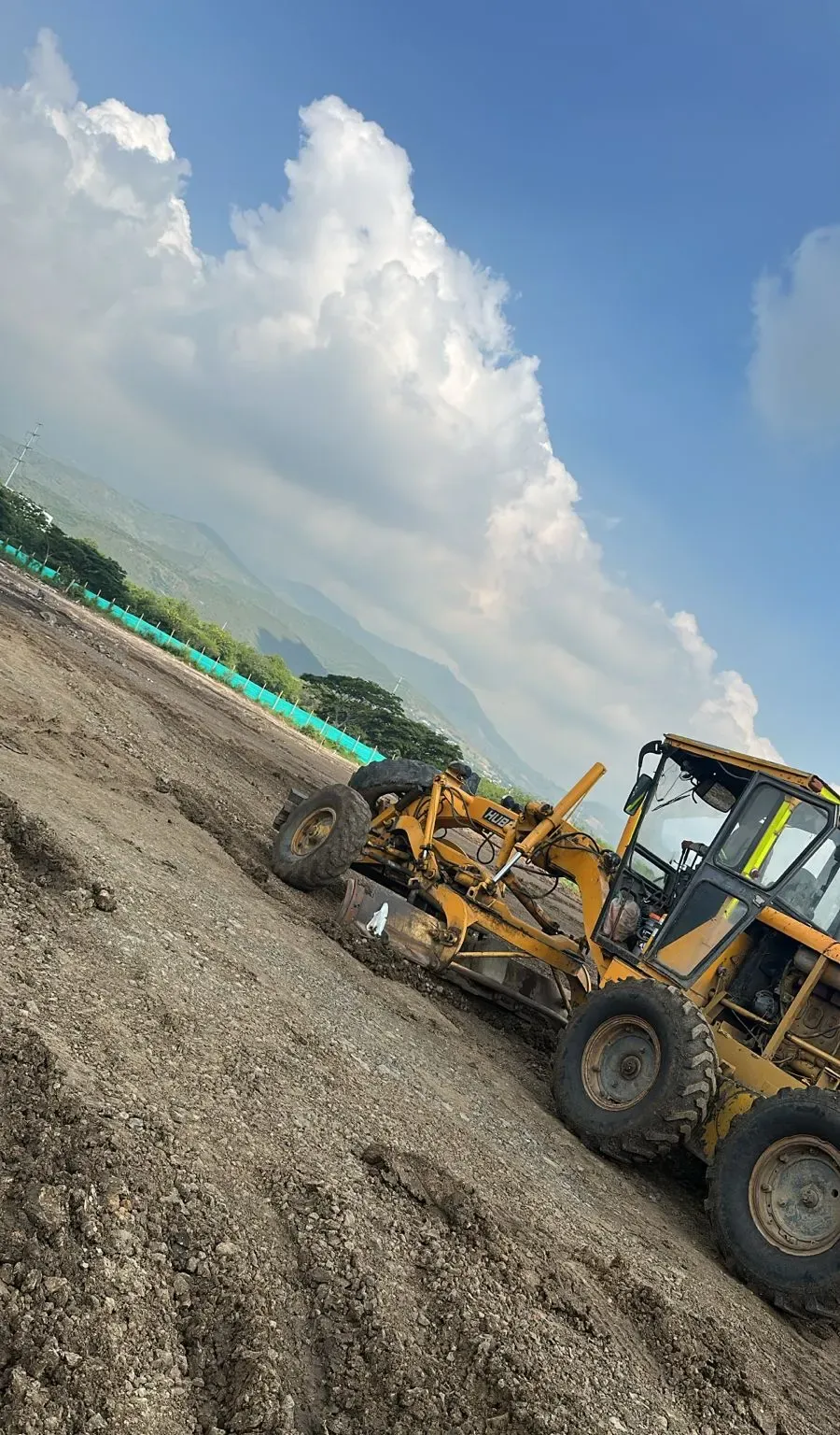 Motoniveladora conformando el terreno de un lote en proceso de nivelación.